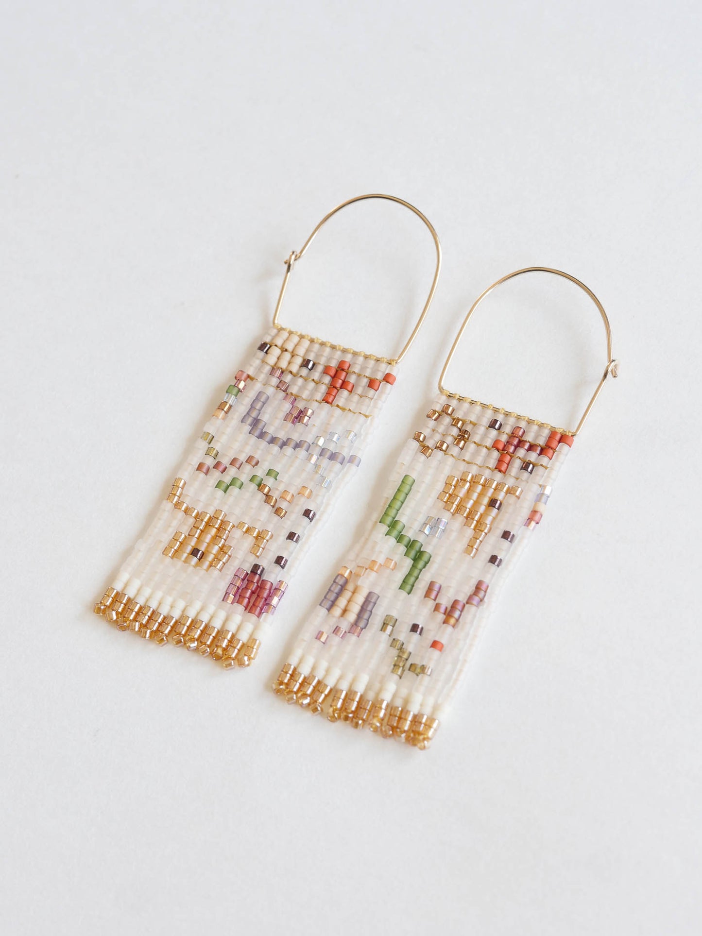 Beaded earrings with gold accents on a light gray background