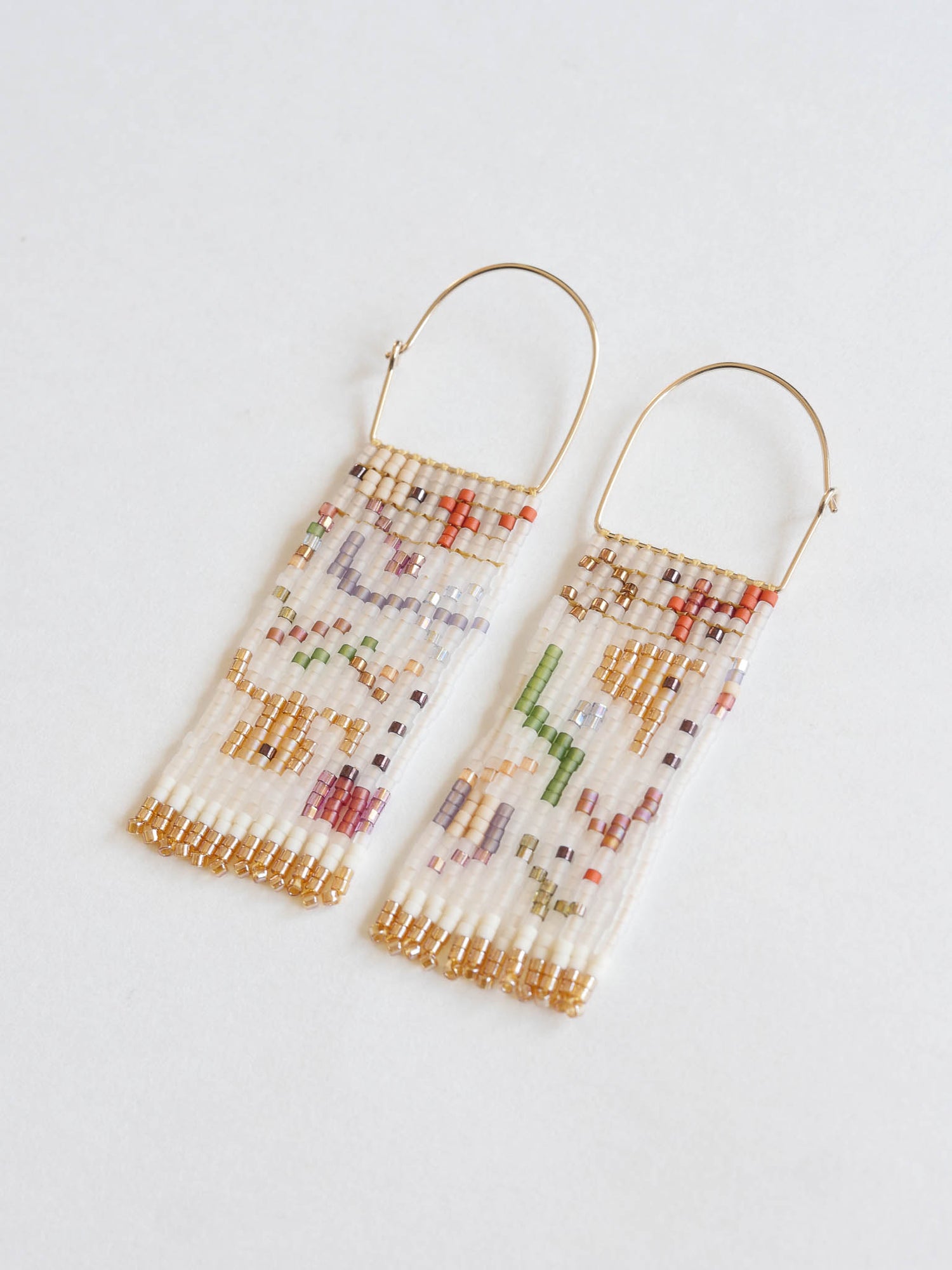 Beaded earrings with gold accents on a light gray background